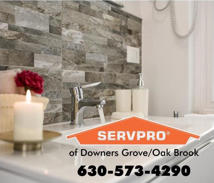 A white bathroom sink with a gray stone backsplash and a white candle.