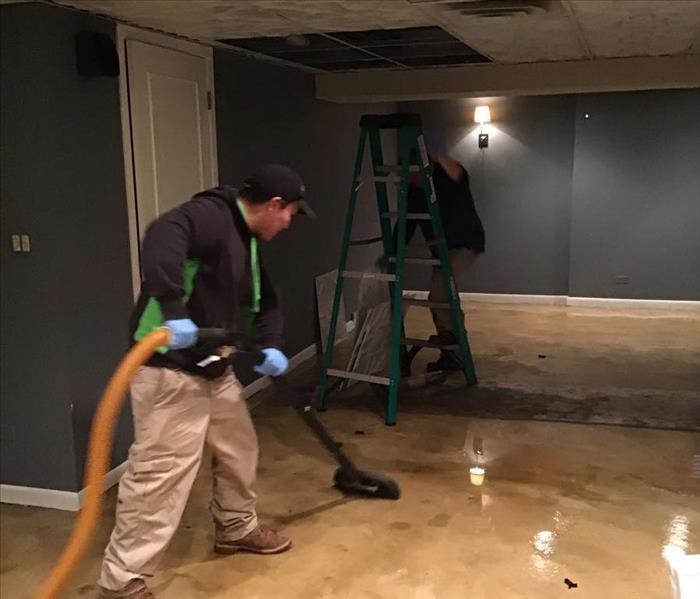 SERVPRO employee removing water from a room with blue walls and a white ceiling.