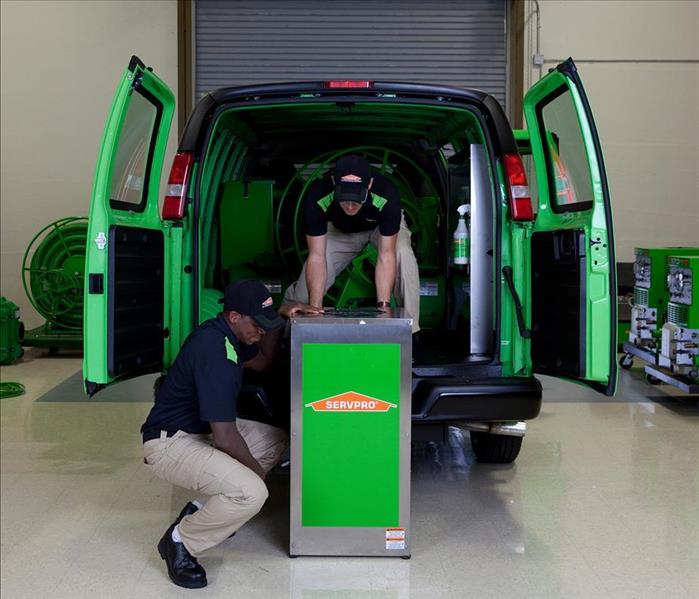 Two SERVPRO employees unloading equipment from a SERVPRO van.