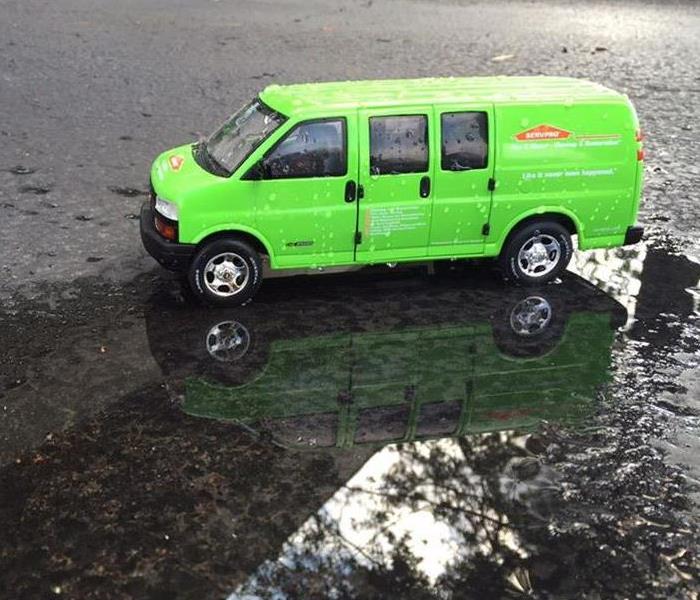 Green SERVPRO van on a wet road.